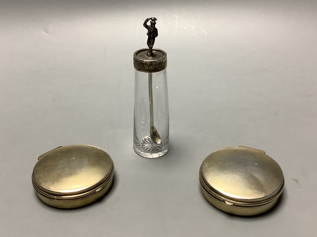 A pair of George V circular silver gilt pill boxes by Asprey Ltd, Birmingham, 1921, 47 mm, together with a silver mounted glass cayenne pepper jar with figural lid.